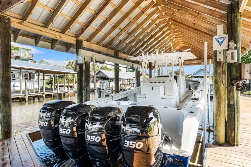  Yacht Photos Pics 2015 Yellowfin 39 boat with triple 350 engines docked under a wooden shelter.