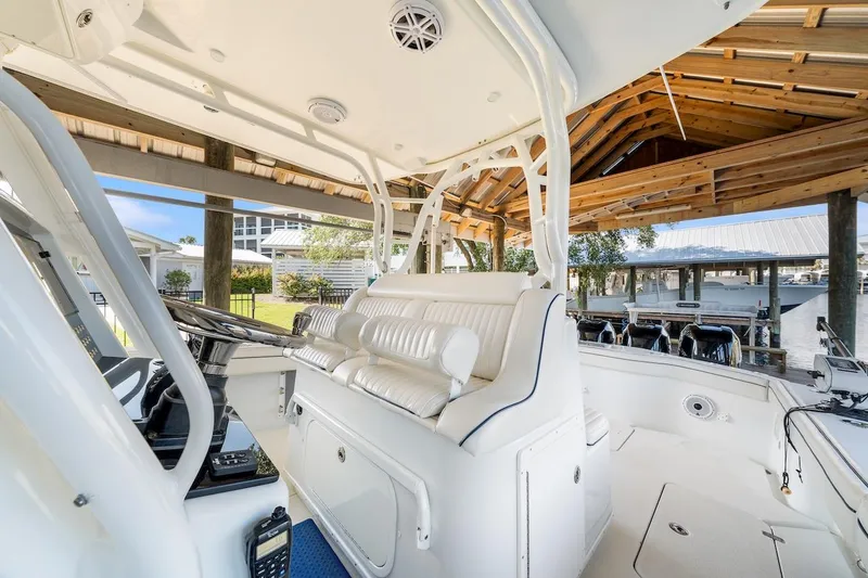  Yacht Photos Pics 2015 Yellowfin 39 boat interior with white seating and helm under a wooden dock shelter.