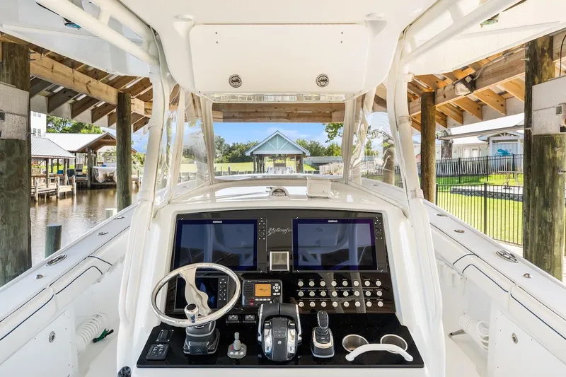  Yacht Photos Pics 2015 Yellowfin 39 boat cockpit with advanced navigation controls, docked under a wooden shelter.