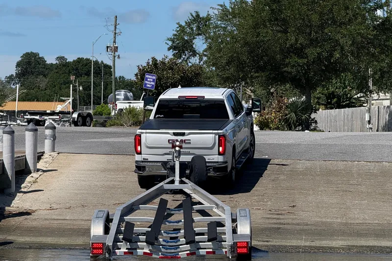 Island Time Yacht Photos Pics Silver GMC truck towing a BARKER 26 trailer at a boat ramp, 2020 model.