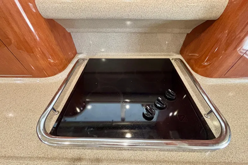  Yacht Photos Pics Stovetop in 2003 Sea Ray 480 Sedan Bridge yacht kitchen, featuring sleek black surface and controls.