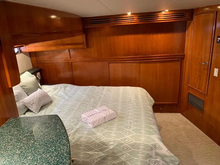 Ocean Life Yacht Photos Pics Luxurious bedroom interior of 2000 Carver 530 Voyager Pilothouse yacht with wood paneling.