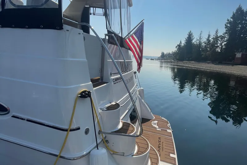 Yacht Photos Pics 2002 Carver 346 Aft Cabin yacht docked by serene waters, American flag displayed.