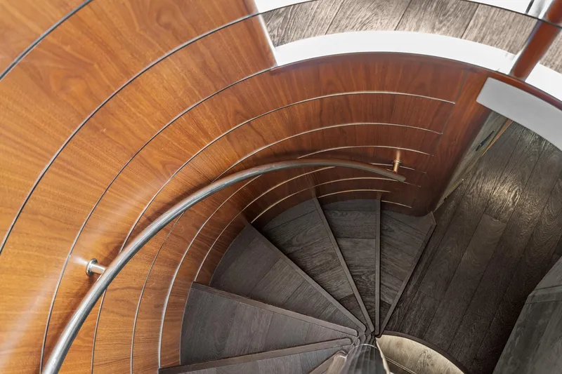 Yacht Photos Pics Spiral staircase on 2014 Sunseeker 75 Yacht with wooden paneling and metal handrail.