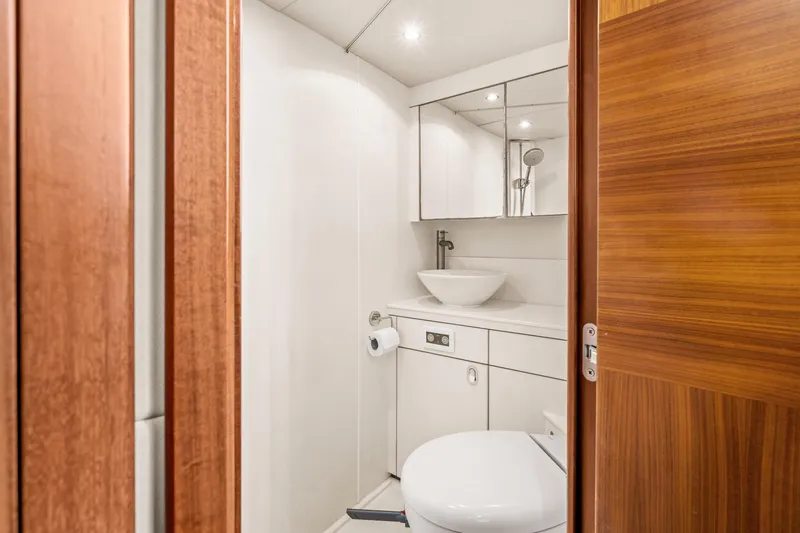  Yacht Photos Pics Modern bathroom on a 2014 Sunseeker 75 Yacht with wooden door and white fixtures.