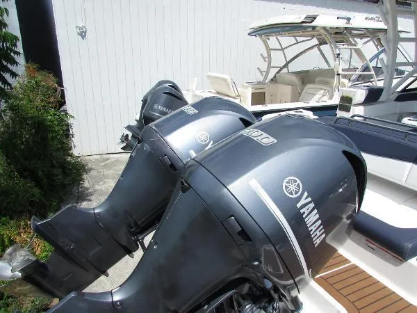 317-147 Ray Brokerage Yacht Photos Pics 2018 Robalo R317 Dual Console with Yamaha outboard engines, docked near a white wall.
