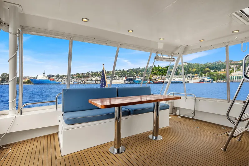 Escencia Yacht Photos Pics 2003 Pacific Mariner Pilothouse yacht interior with blue seating and wooden table, overlooking marina.