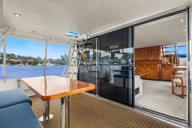 Escencia Yacht Photos Pics 2003 Pacific Mariner Pilothouse yacht interior with wooden table, seating, and waterfront view.