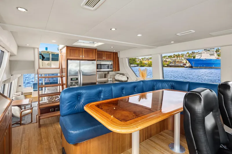 Escencia Yacht Photos Pics Luxurious 2003 Pacific Mariner Pilothouse interior with blue seating, wooden table, and modern kitchen.