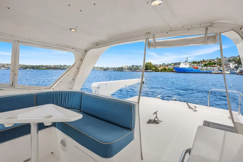 Escencia Yacht Photos Pics 2003 Pacific Mariner Pilothouse yacht interior with blue seating, overlooking serene waters and distant shoreline.