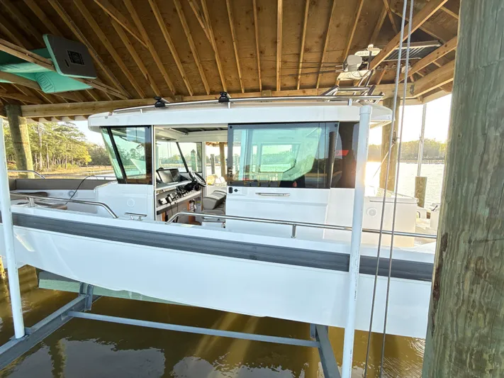  Yacht Photos Pics 2019 Axopar 28 CABIN boat docked under wooden shelter.