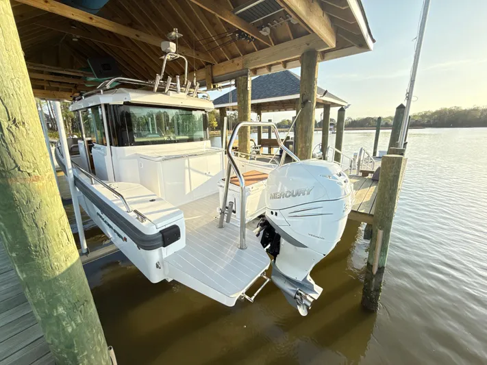  Yacht Photos Pics 2019 Axopar 28 CABIN boat docked under a wooden shelter with Mercury outboard engine.
