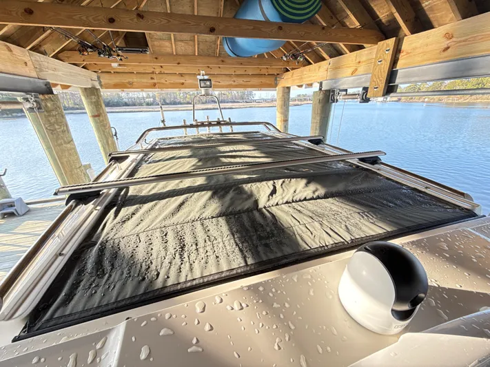  Yacht Photos Pics Axopar 28 CABIN 2019 boat under wooden dock, with water droplets on the roof.