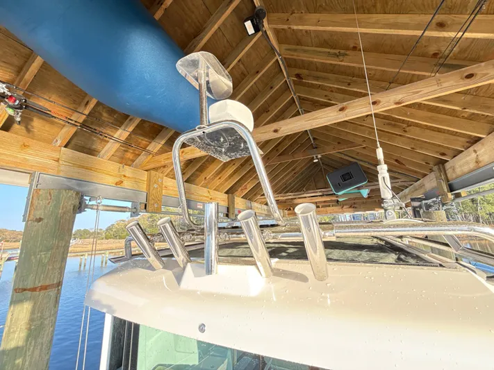  Yacht Photos Pics 2019 Axopar 28 CABIN boat under wooden dock roof, featuring rod holders and equipment.