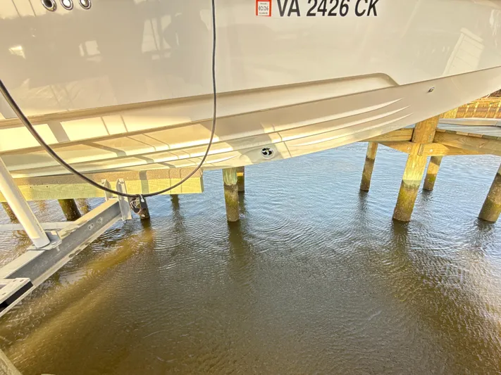  Yacht Photos Pics 2019 Axopar 28 CABIN boat on lift above water, showing hull and registration.