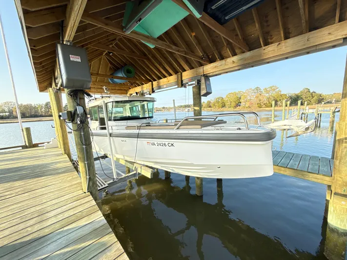  Yacht Photos Pics 2019 Axopar 28 CABIN boat docked under a wooden shelter by the water.