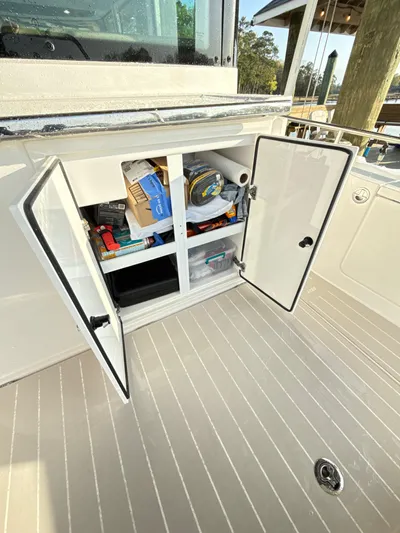  Yacht Photos Pics 2019 Axopar 28 CABIN storage compartment with open doors, revealing organized boating supplies.