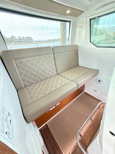  Yacht Photos Pics 2019 Axopar 28 CABIN interior with beige quilted seating and large windows.