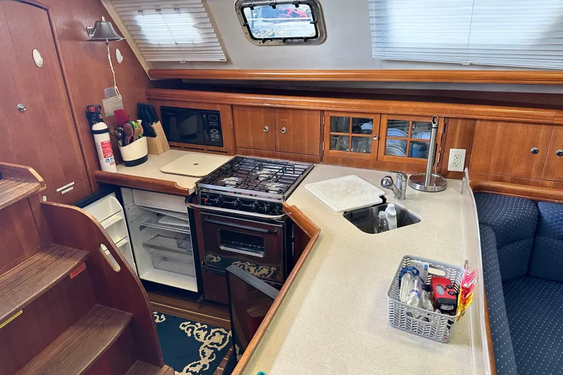 Ms Bea Haven Yacht Photos Pics 2006 Hunter 41 Deck Salon interior kitchen with stove, sink, and wooden cabinetry.