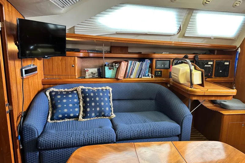 Ms Bea Haven Yacht Photos Pics Interior of 2006 Hunter 41 Deck Salon with blue sofa, TV, and navigation station.