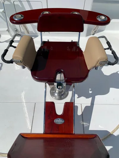 Pier Pressure Yacht Photos Pics Luxury fishing chair on 2000 Viking 50 Convertible yacht, featuring polished wood and cushioned armrests.