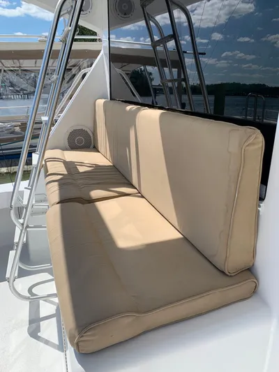 Pier Pressure Yacht Photos Pics Beige cushioned seating on 2000 Viking 50 Convertible yacht, with metal frame and outdoor view.