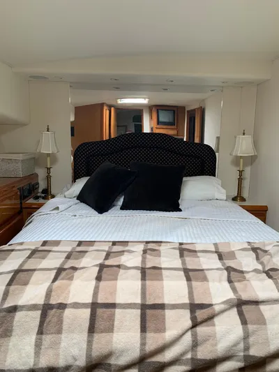 Pier Pressure Yacht Photos Pics Interior of 2000 Viking 50 Convertible yacht bedroom with bed, lamps, and plaid blanket.