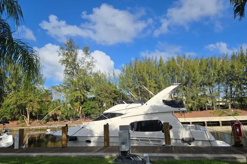  Yacht Photos Pics 2001 Silverton 410 Sport Bridge yacht docked by lush trees under a blue sky.
