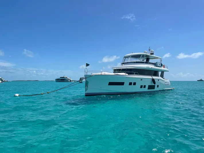 Fantasea Yacht Photos Pics Luxurious 2020 Sirena 64 yacht anchored in clear turquoise waters under a bright blue sky.