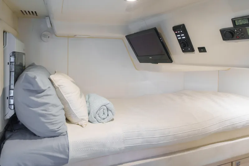 Fantasea Yacht Photos Pics Cozy cabin interior of 2020 Sirena 64 yacht with bed, pillows, and electronics.