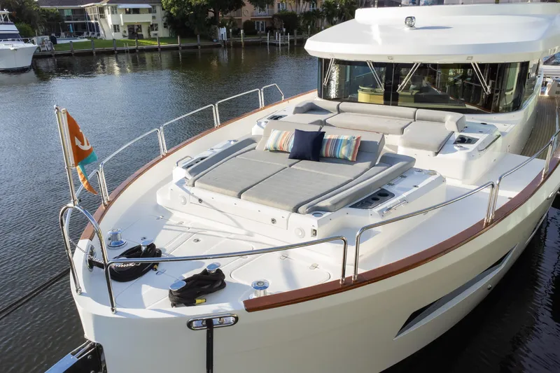 Fantasea Yacht Photos Pics Luxurious 2020 Sirena 64 yacht with spacious sun deck and cushions, docked by waterfront homes.