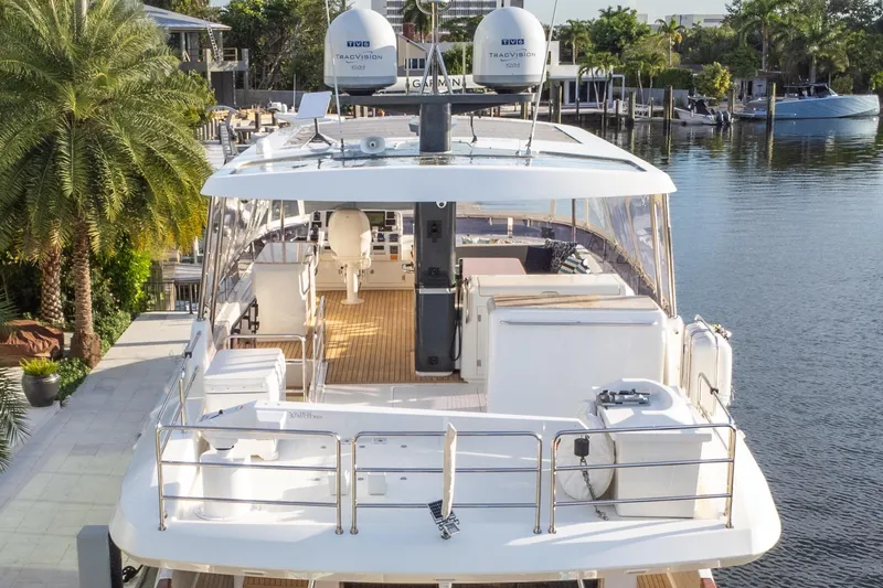 Fantasea Yacht Photos Pics Luxury Sirena 64 yacht, 2020 model, docked by a scenic waterfront with lush greenery.