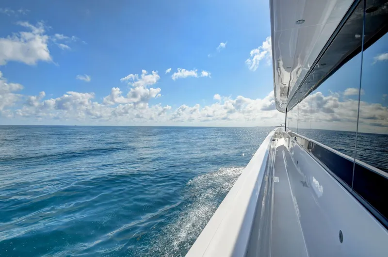 Danielle Yacht Photos Pics Side view of 2005 Hatteras Semi-Displacement yacht cruising on open sea under blue sky.