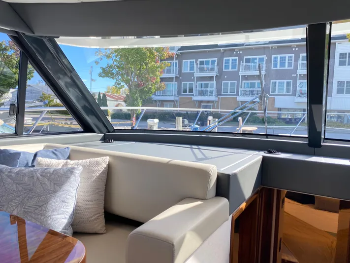  Yacht Photos Pics Interior view of 2025 Riviera 465 SUV yacht with plush seating and marina backdrop.