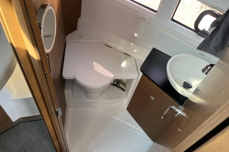  Yacht Photos Pics 2020 Jeanneau NC 895 boat bathroom with toilet, sink, and wooden cabinetry.