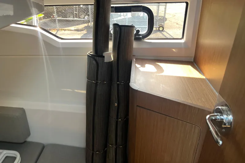  Yacht Photos Pics Interior of 2020 Jeanneau NC 895 boat with window, seating, and wooden cabinetry.