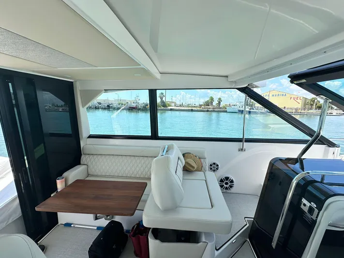  Yacht Photos Pics Interior of 2023 Regal Grande Coupe yacht with seating and table, overlooking marina.