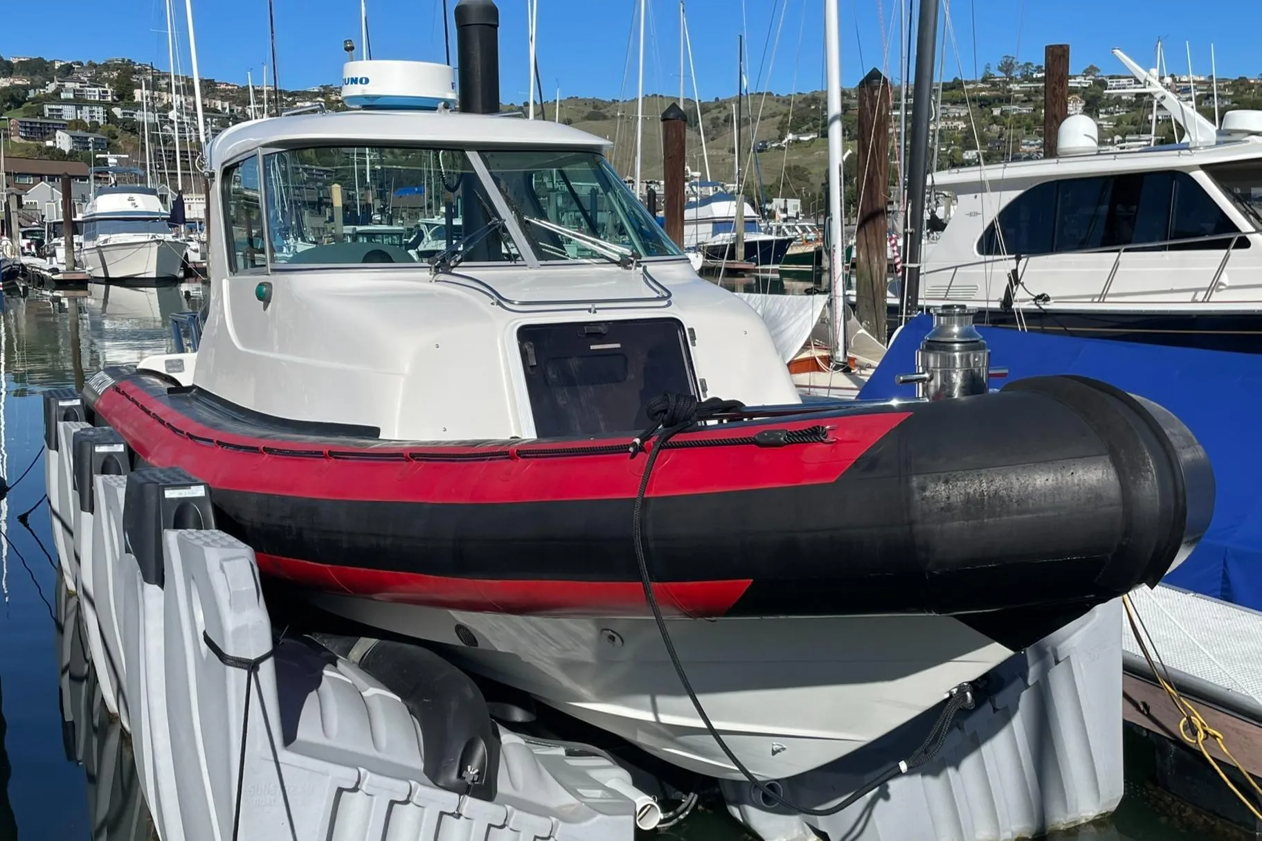 2001 Protector Targa 28 boat docked in a marina, featuring a red and black hull.