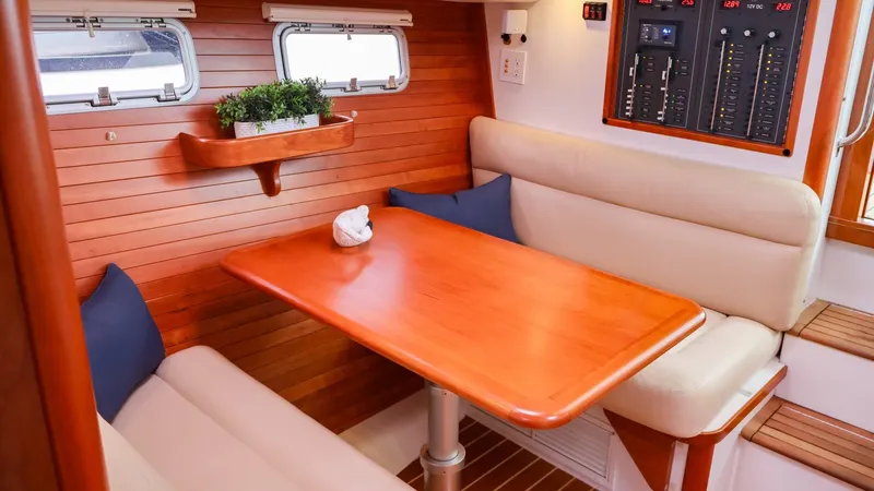 4709tw Yacht Photos Pics 2010 MJM 40z Downeast boat interior, cozy dining area with wooden table and cushioned seating.