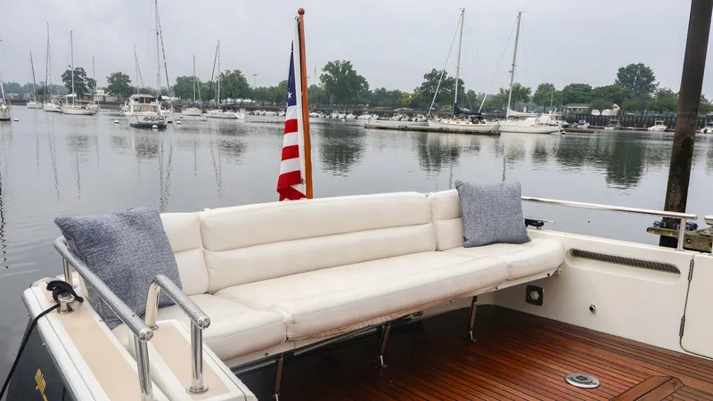 4709tw Yacht Photos Pics 2010 MJM 40z Downeast boat with white seating and American flag in a marina.
