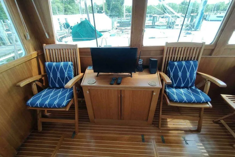Summersalts Yacht Photos Pics Interior of 1996 Grand Banks Eastbay 40 Flybridge with wooden chairs and a small TV.