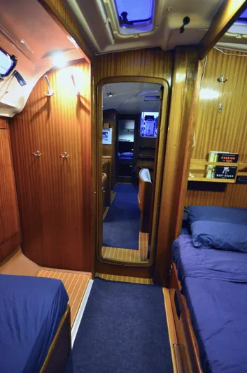 Footloose Yacht Photos Pics Interior of 2003 Bavaria 49 yacht cabin with wooden paneling and blue bedding.