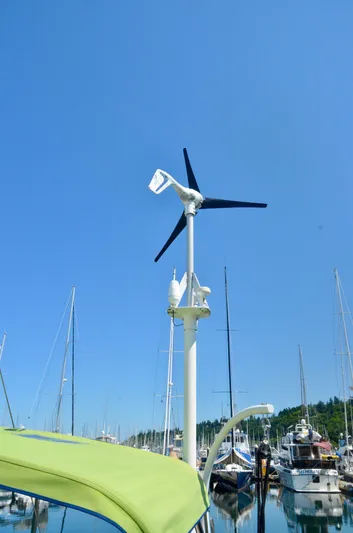 Footloose Yacht Photos Pics Wind turbine on Bavaria 49 yacht, 2003 model, docked in a marina under clear blue sky.