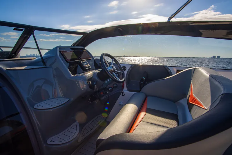 Ready For Delivery! Yacht Photos Pics Interior of 2025 Hanover 305 Outboard boat, featuring black and orange seating, steering wheel, and dashboard.