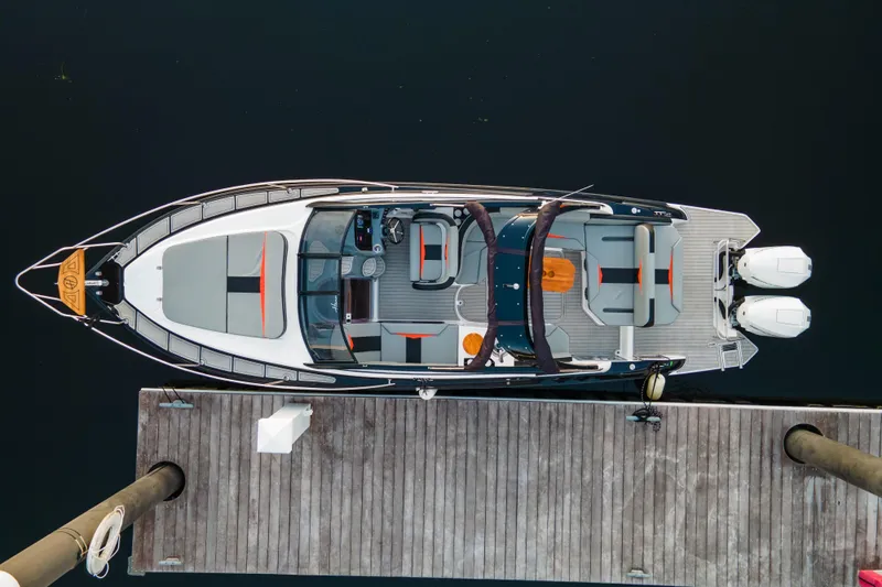 Ready For Delivery! Yacht Photos Pics Top view of 2025 Hanover 305 Outboard boat, black and orange, docked.