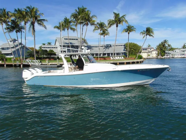  Yacht Photos Pics 2016 Edgewater 368 CC boat on water, with palm trees and houses in the background.