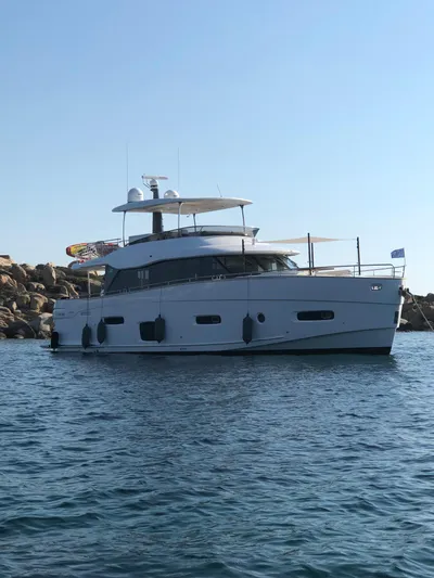  Yacht Photos Pics Azimut Magellano 66 yacht, 2019 model, anchored in calm waters near rocky shoreline.