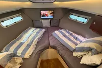 Cozy cabin interior of 2024 Nimbus 305 Coupe with striped bedding and TV.