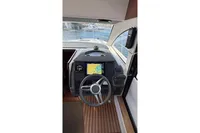 2024 Nimbus 305 Coupe helm with navigation display and steering wheel, overlooking water.