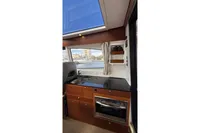 Interior of 2024 Nimbus 305 Coupe boat with modern kitchen and scenic window view.